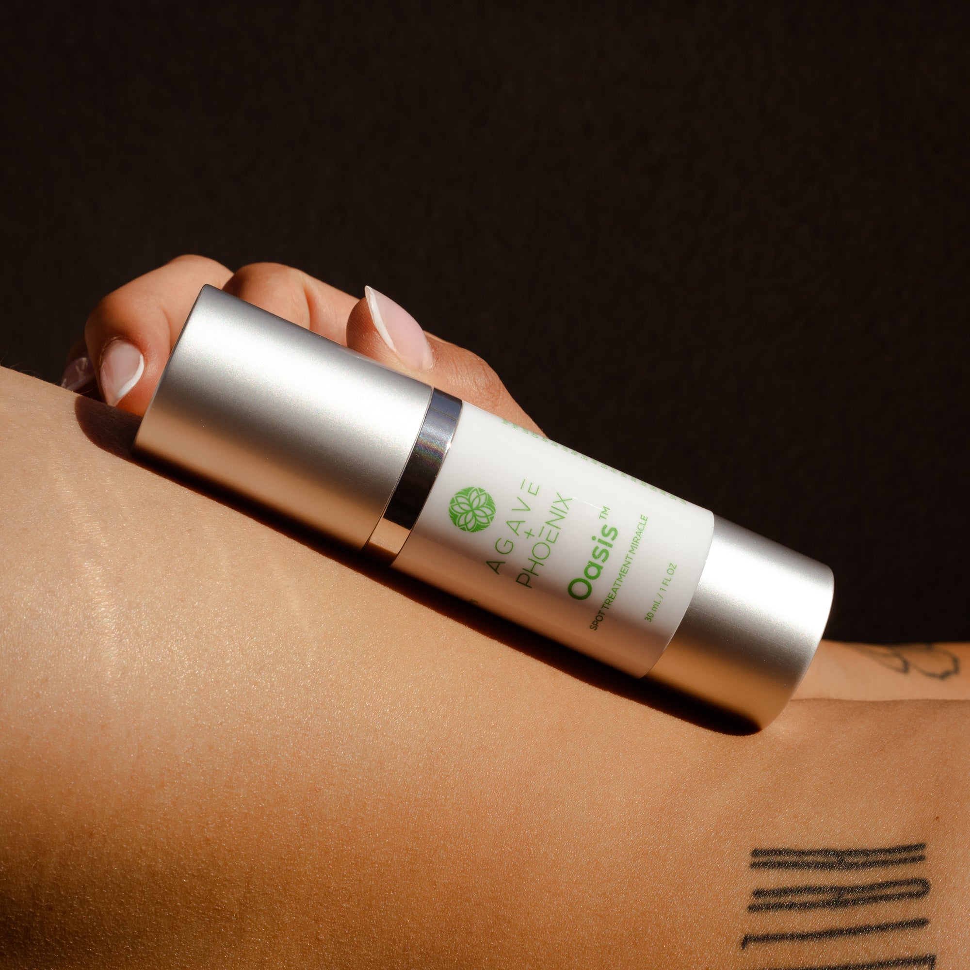 Oasis Spot Treatment resting on model’s back — plant-powered care for blemishes, uneven tone, and fine lines.